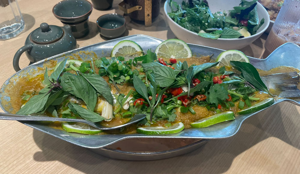 Fish covered with basil leaves on a fish-shaped platter