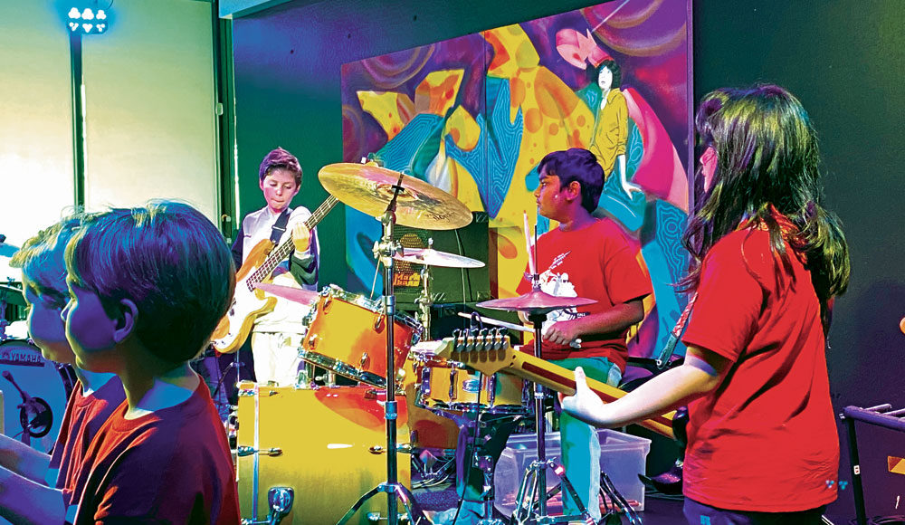 Young kids playing rock instruments on a stage