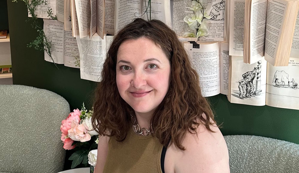 Woman sitting in front of a wall covered with pages from books