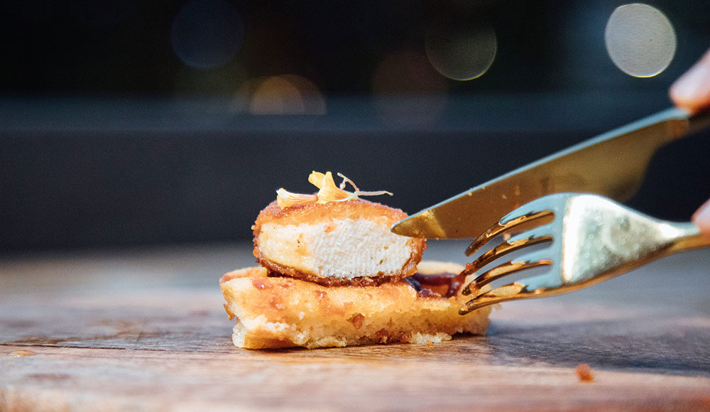 knife and fork by a small piece of meat that looks like chicken