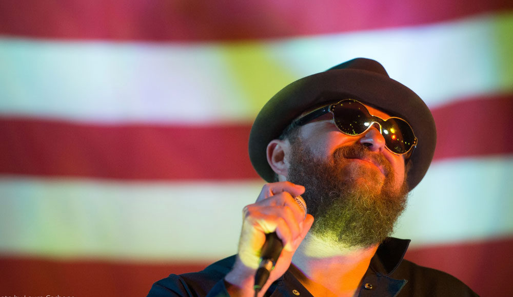 Man holding a microphone in front of an American flag