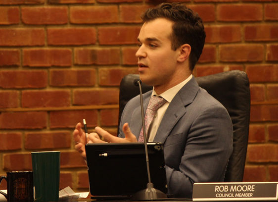 Man in profile sitting at a desk, looking at someone off camera