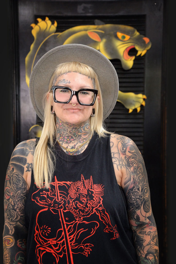 Woman in big eyeglasses with tattoos on her arms and neck