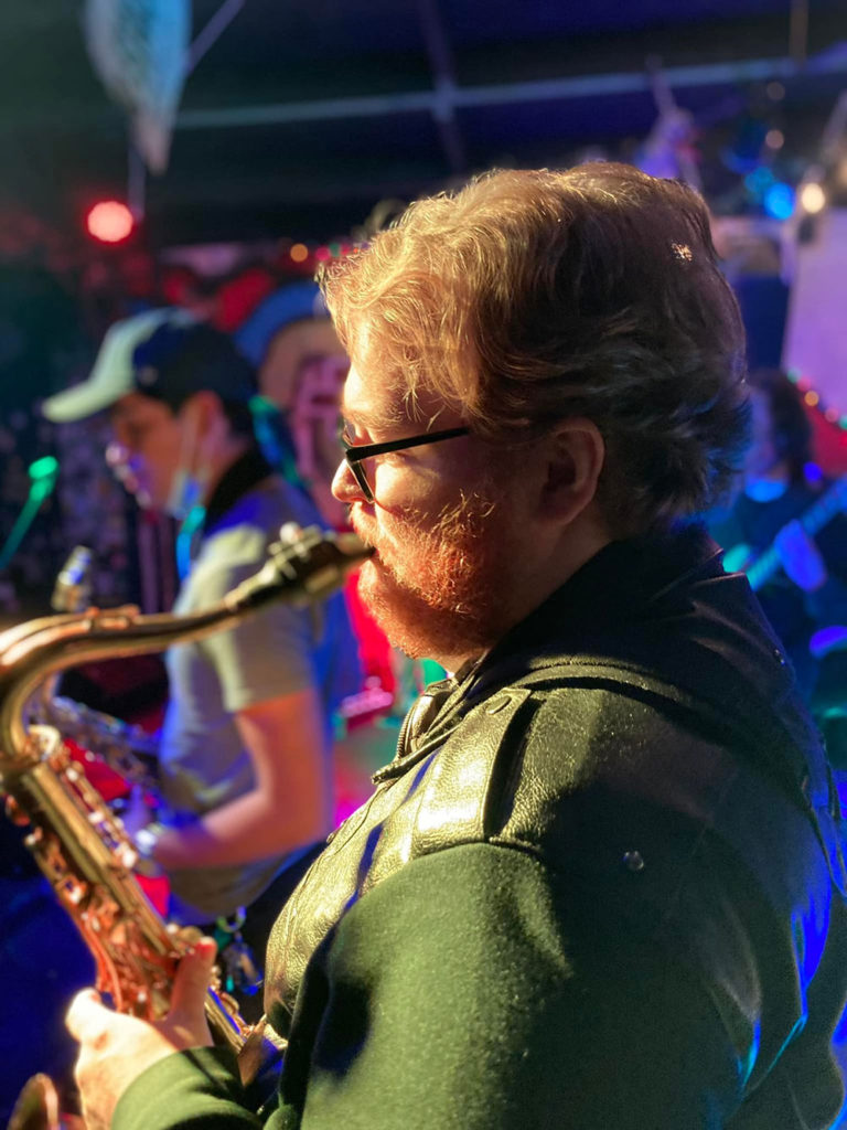 Musician onstage playing a saxophone with another musician in the background