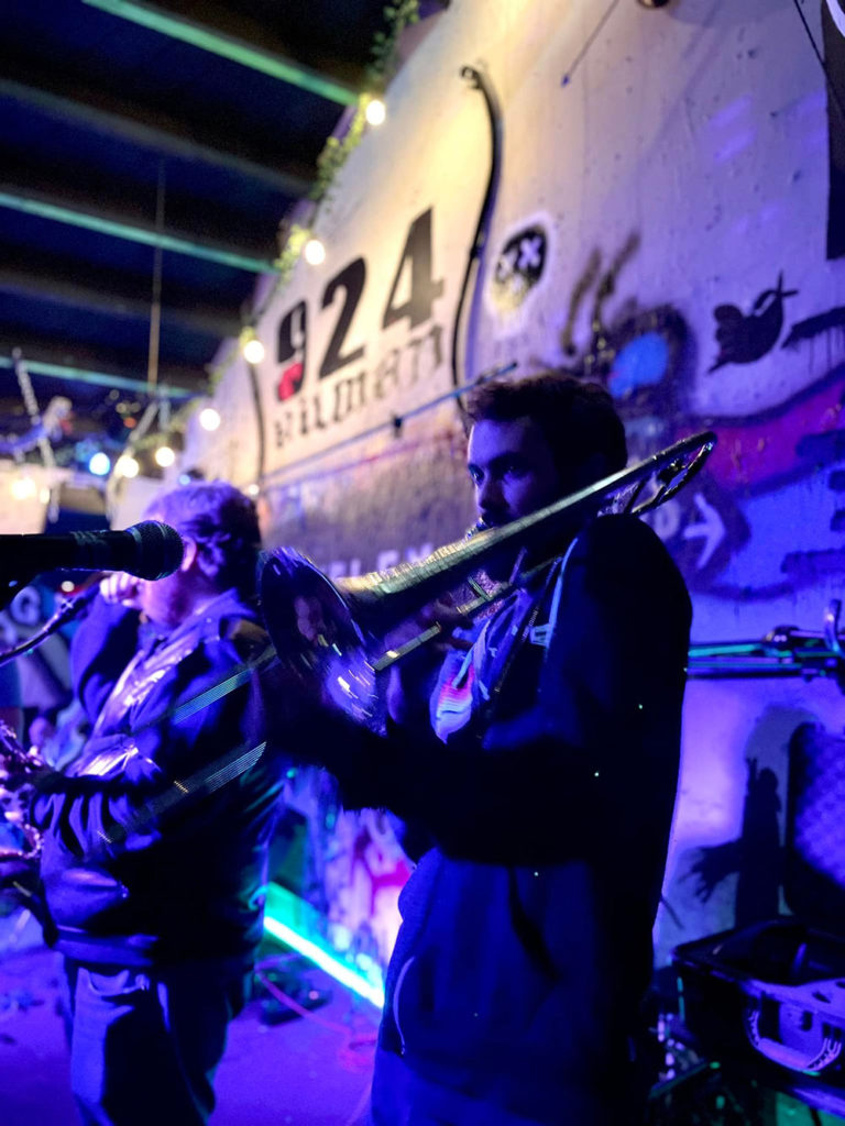 Musician playing a trombone with other members of the band in the background