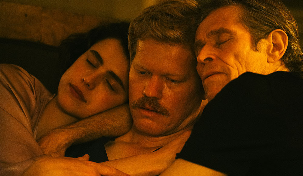 Three actors holding each other closely, appearing to be in bed