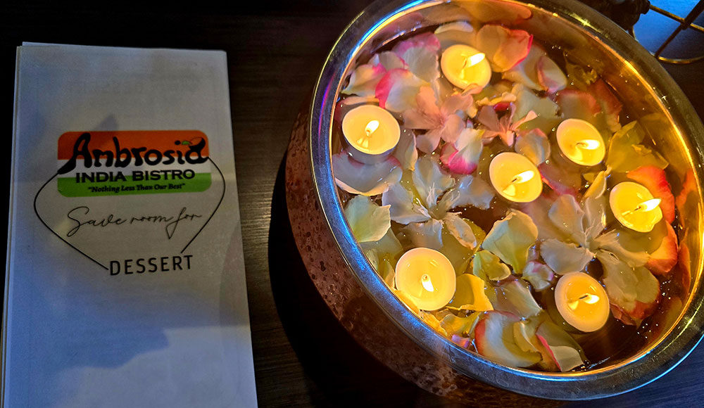 Ambrosia India Bistro menu next to floating candles and rose petals