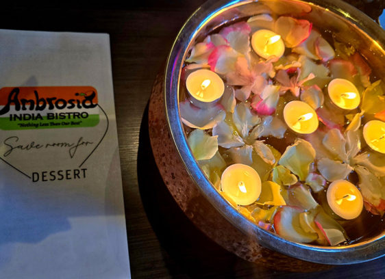 Ambrosia India Bistro menu next to floating candles and rose petals