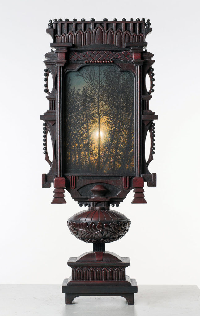 Tall wooden sculptural object that fuctions as a frame for a landscape painting within it.