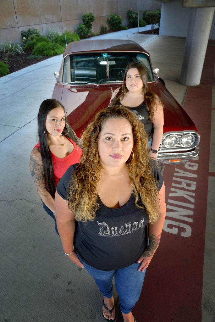 Three women standing in front of a vintage car