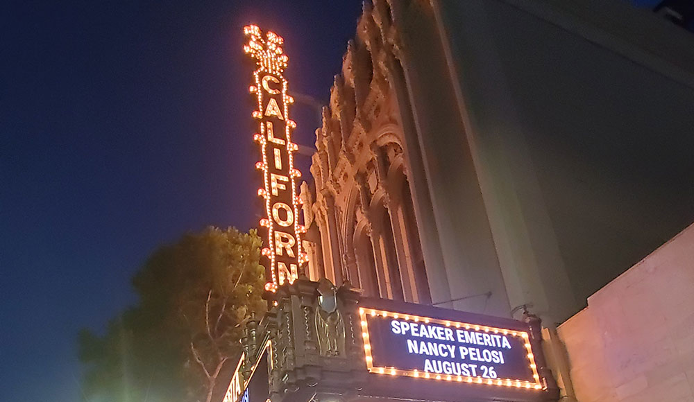 Front of a theater with the marquee advertising an appearance by Nancy Pelosi