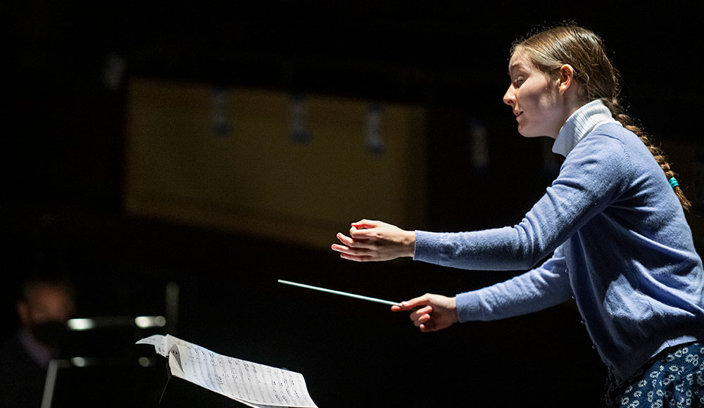 Young woman holding a baton on the conductor stand