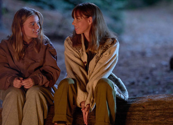 Two women sitting outside on a log