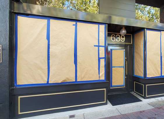 Storefront with windows taped up and a plaque on the side