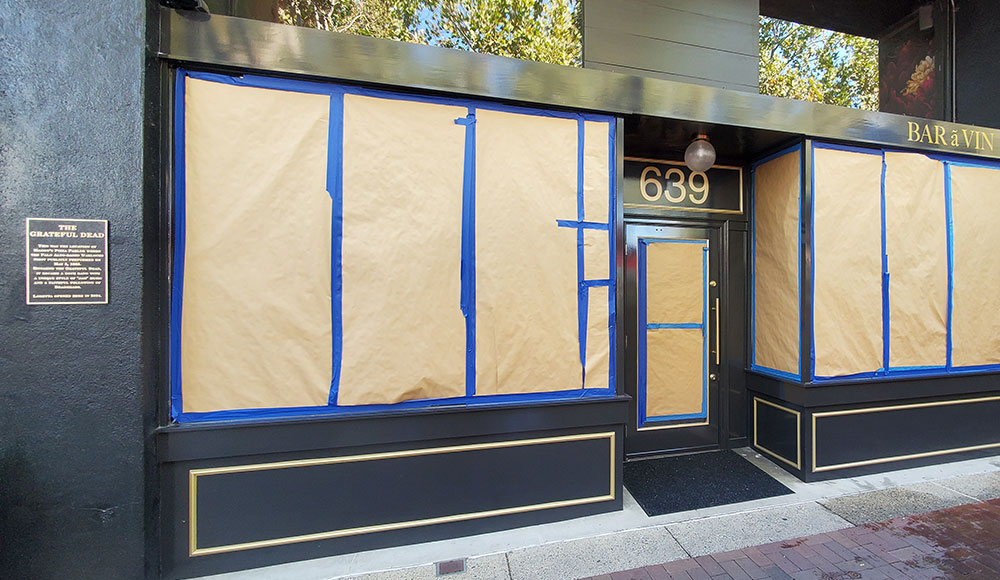 Storefront with windows taped up and a plaque on the side