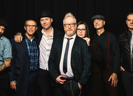 Seven people standing against a black background