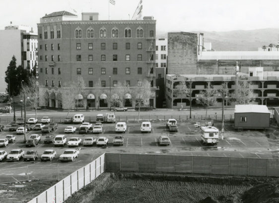 Black and white photo of parking lot in front of an old hotel