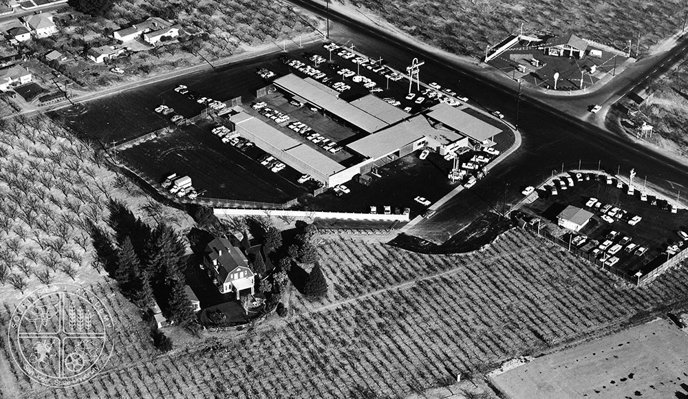 Archival aerial view of an area where orchards are giving way to commercial development