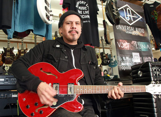 Man playing a red electric guitar in a music store