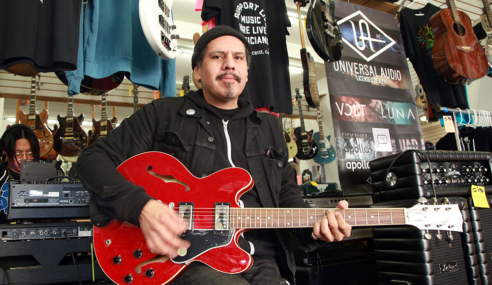 Man playing a red electric guitar in a music store