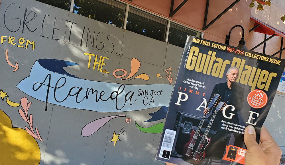 Hand holding up a magazine in front of a boarded-up building