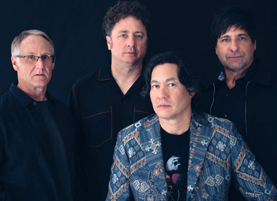 Four men posing for a group portrait on a dark background