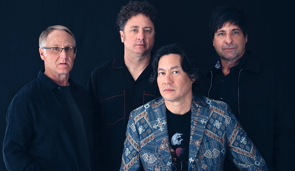 Four men posing for a group portrait on a dark background