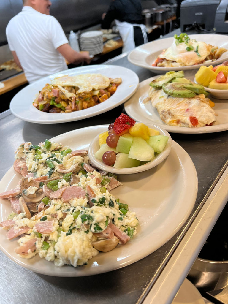 Plates of food coming out of a kitchen and ready to be picked up by wait staff