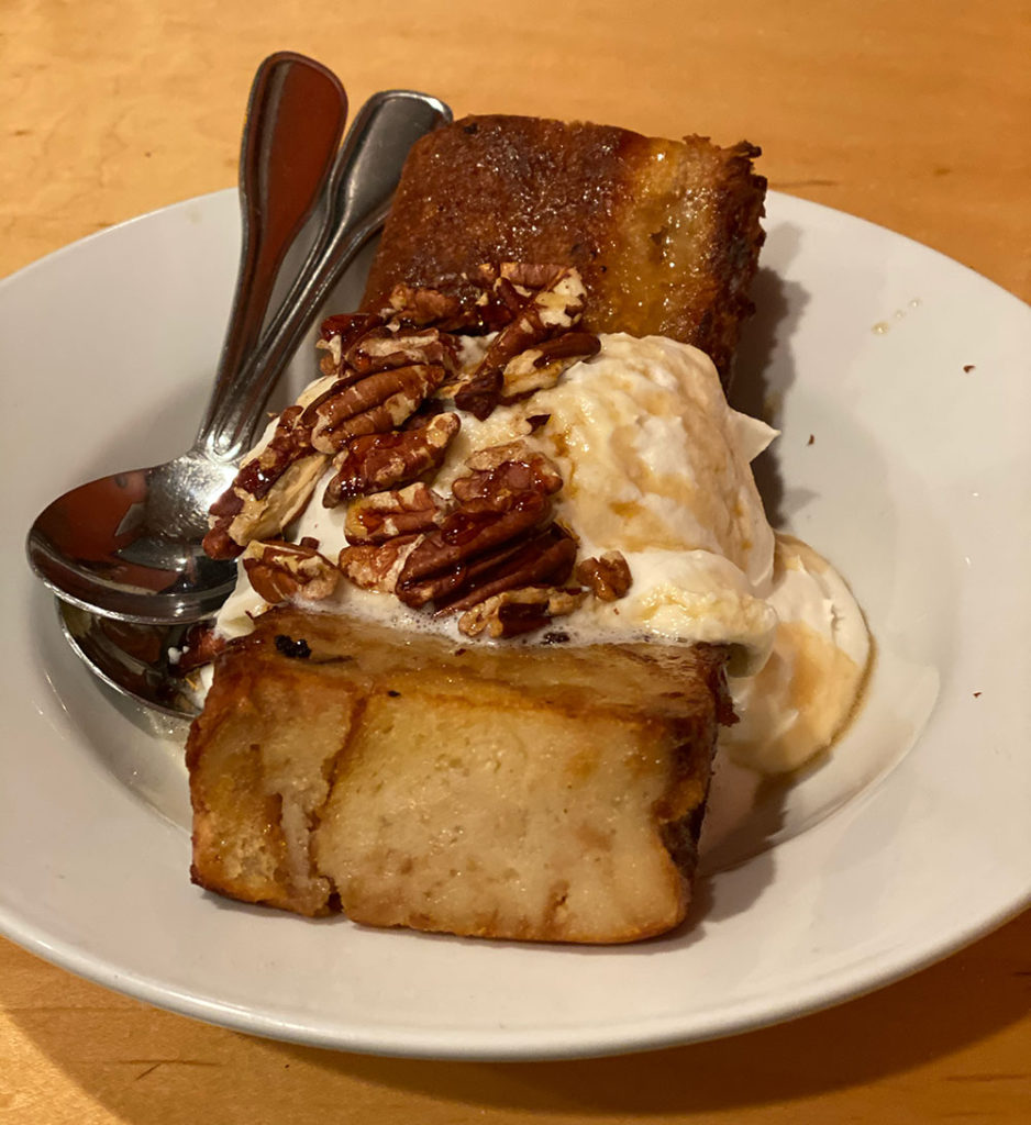 Slice of bread pudding with whipped cream and nuts on top