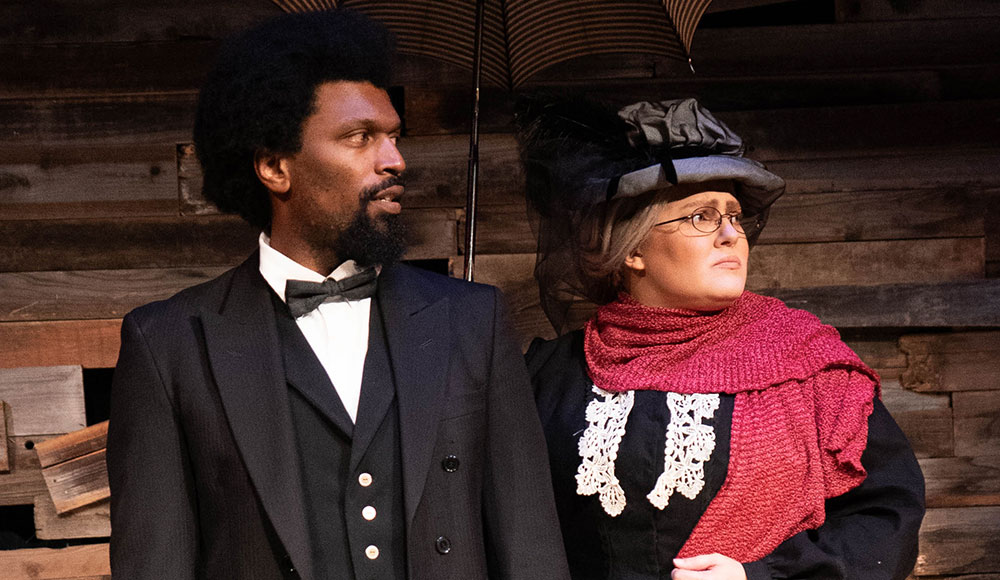 Black man and white woman in 19th century clothing on a stage