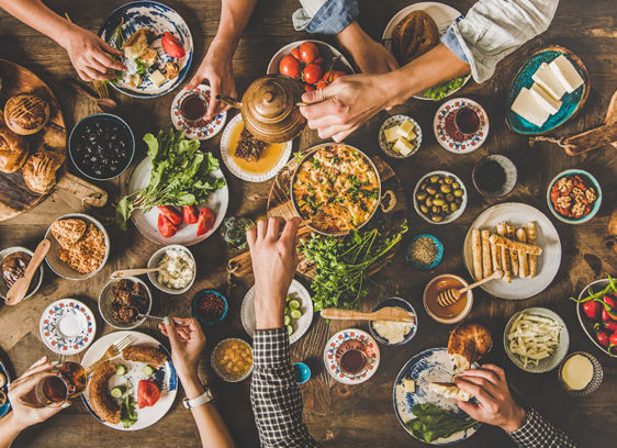 Arms outstretched over a table loaded with food