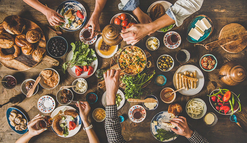 Arms outstretched over a table loaded with food