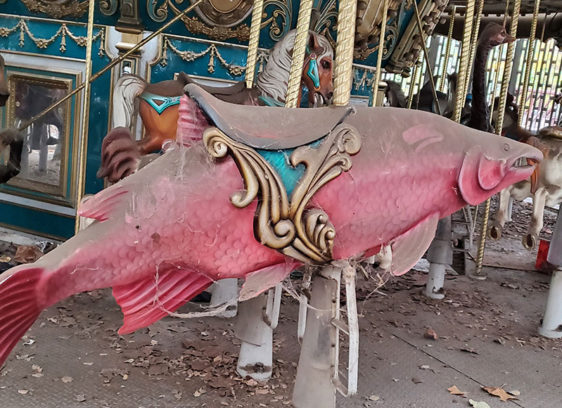 Salmon-shaped seat on a dusty, out-of-commission carousel