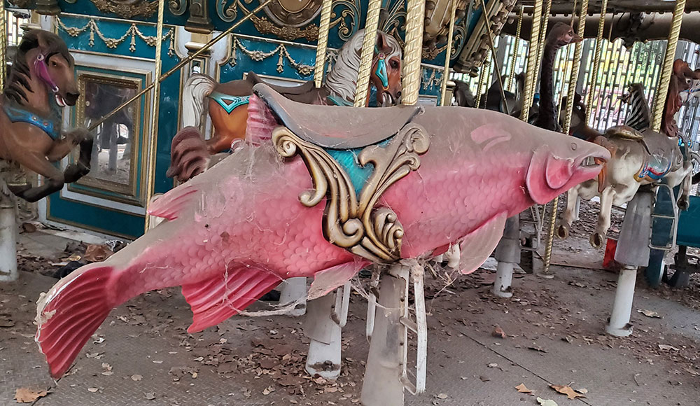 Salmon-shaped seat on a dusty, out-of-commission carousel