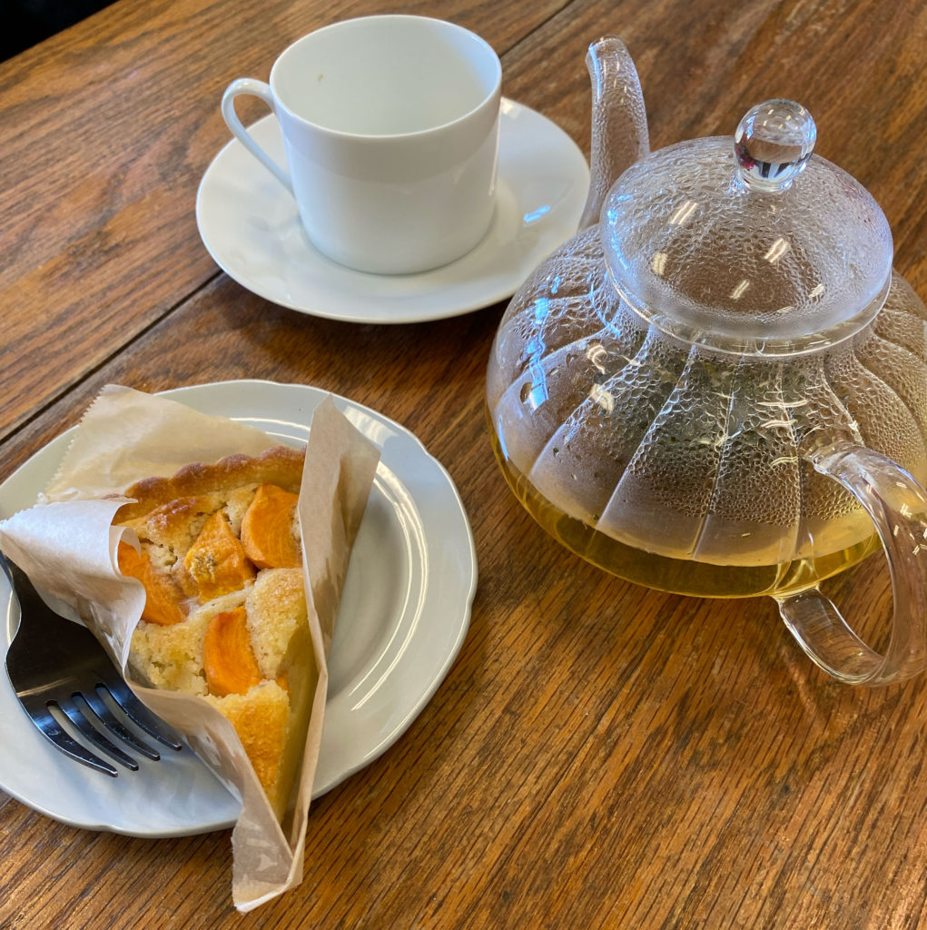 Triangular sliced tart with teapot and a cup on a table