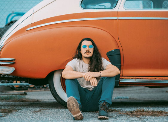 Man sitting in front of a vintage sedan