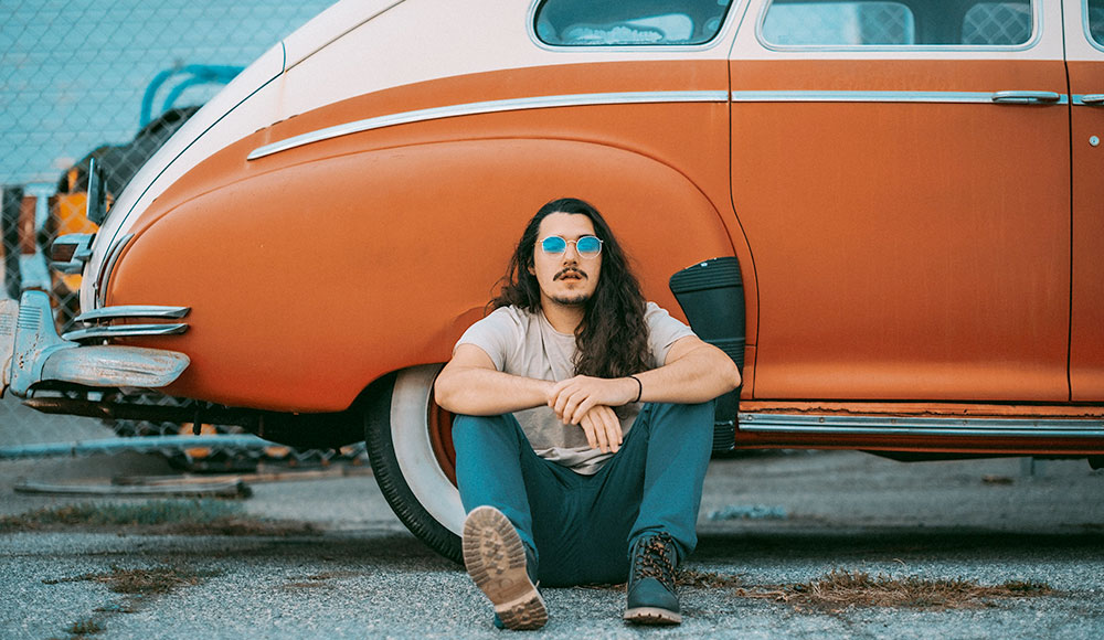 Man sitting in front of a vintage sedan