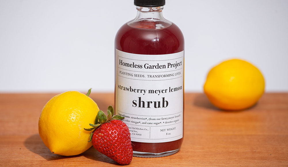 Glass bottle next to two lemons and a strawberry