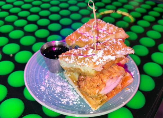 Plate with chicken and waffles on top of a table decorated with neon green golf balls