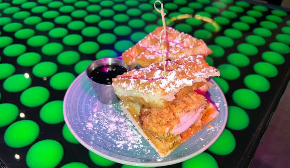 Plate with chicken and waffles on top of a table decorated with neon green golf balls