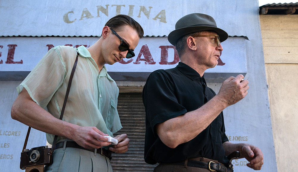 Two men walking down a street with signs on the buildings in Spanish