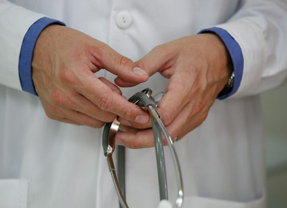 Hands holding stethoscope in front of a white coat