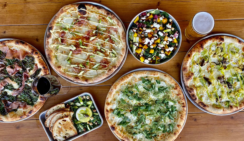 several pizzas and side dishes on a table