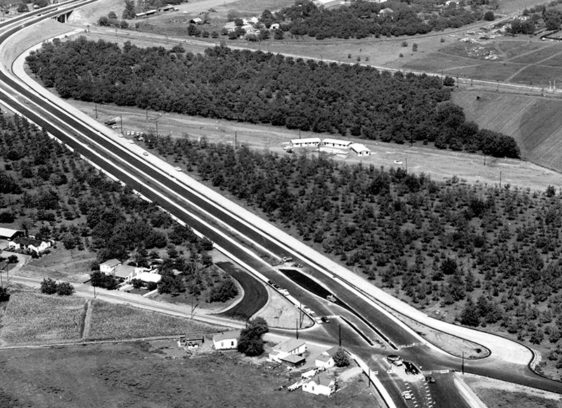 Aerial view of a highway traversing agricultural land, with new development sprouting up