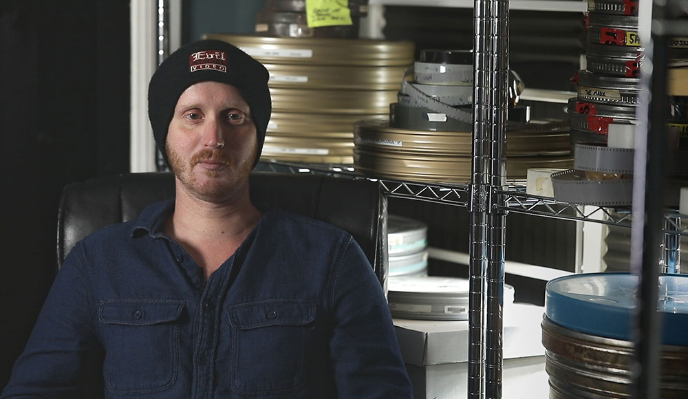 Man in a storage room surrounded by film reels